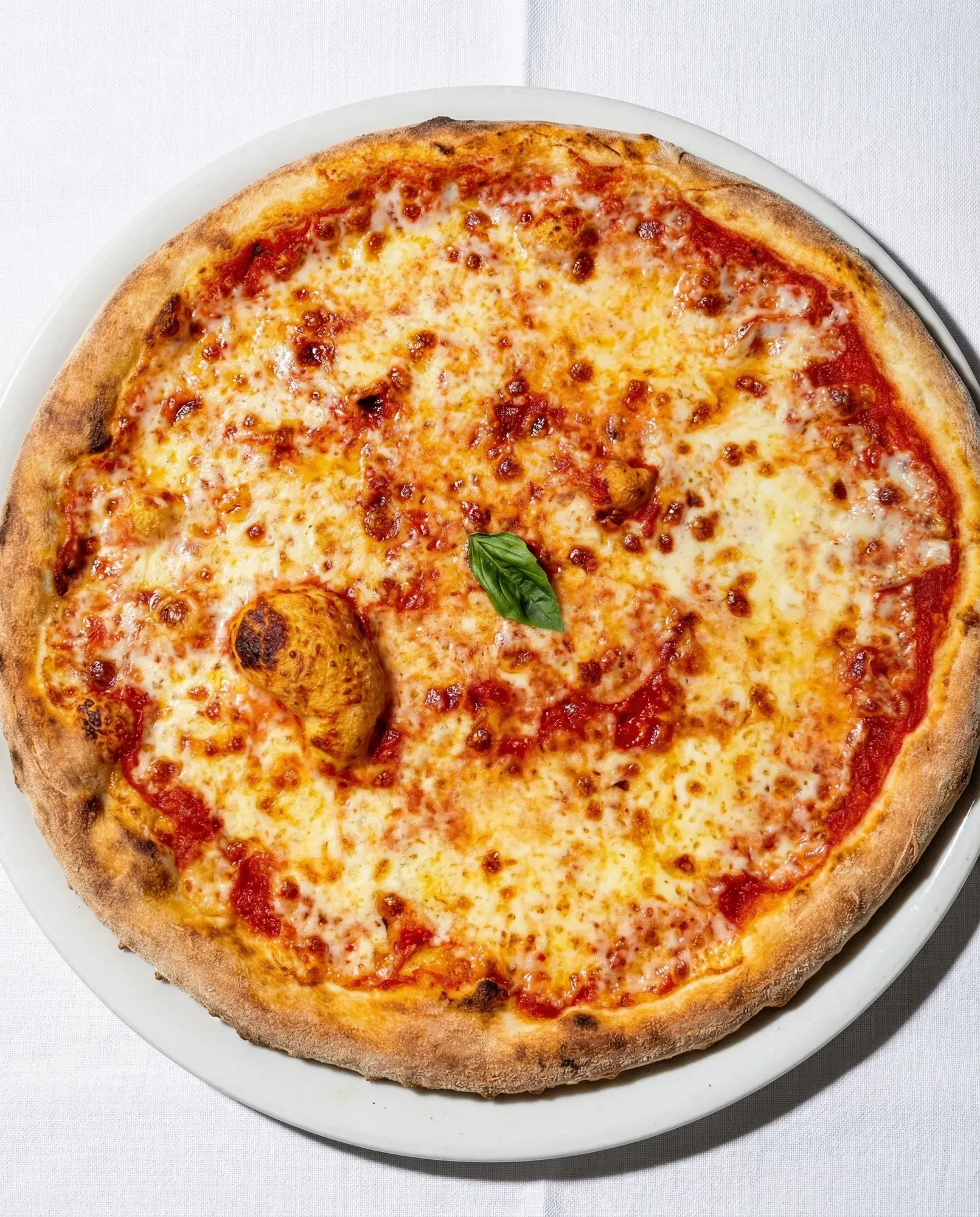 Pizza Margherita von oben auf weiß gedecktem Tisch bei La Commedia.