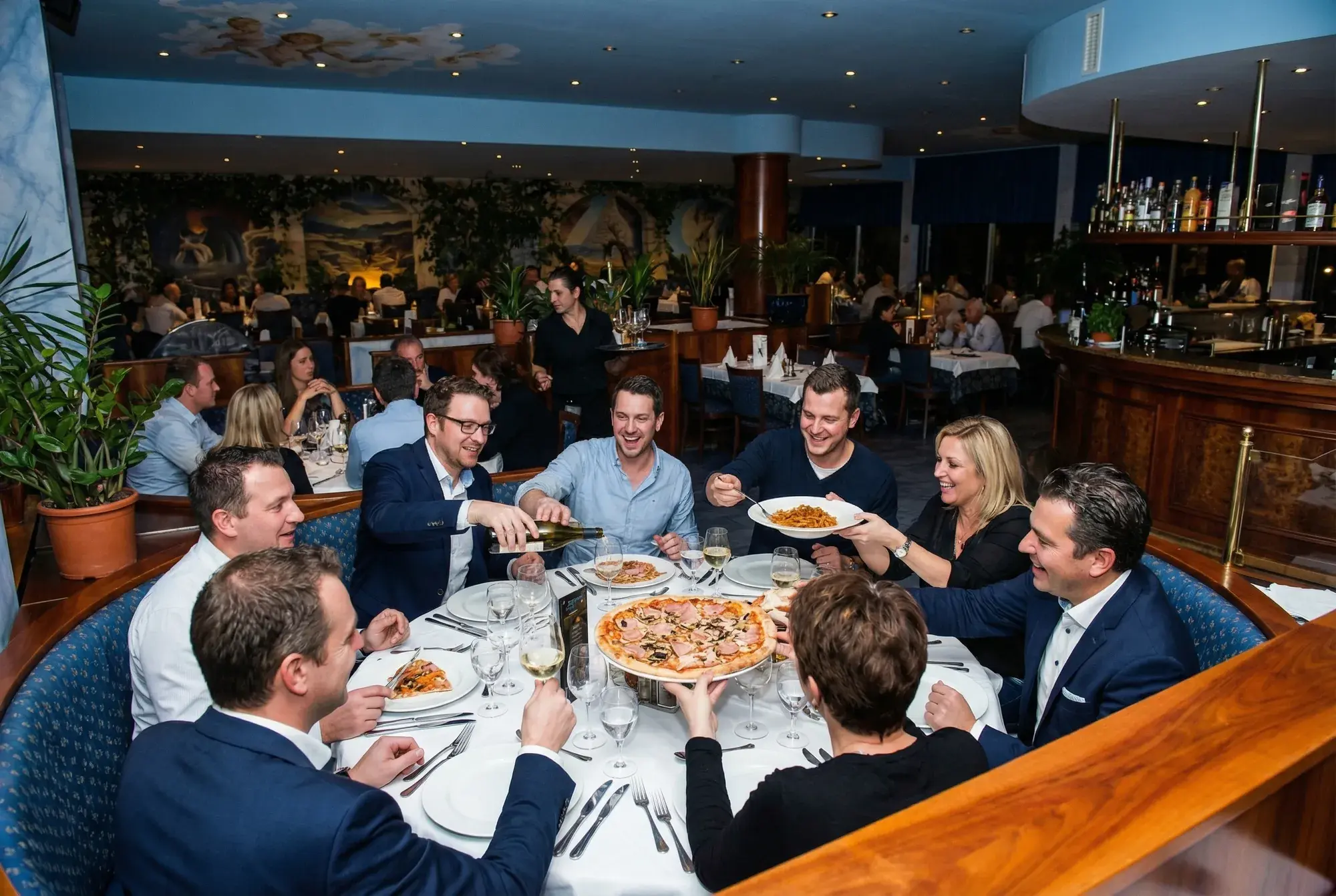 Große Runde im Gastraum von La Commedia mit Service und gedecktem Tisch.