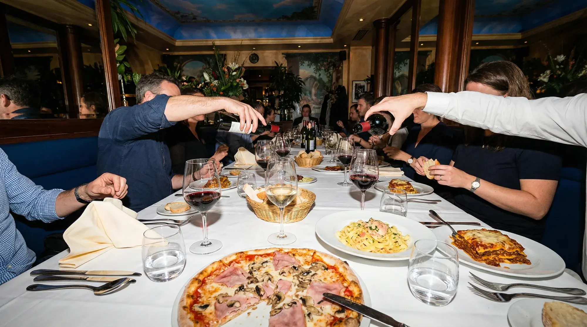 Lange Tafel mit Wein, Pizza und Pasta bei einer Feier im Restaurant.
