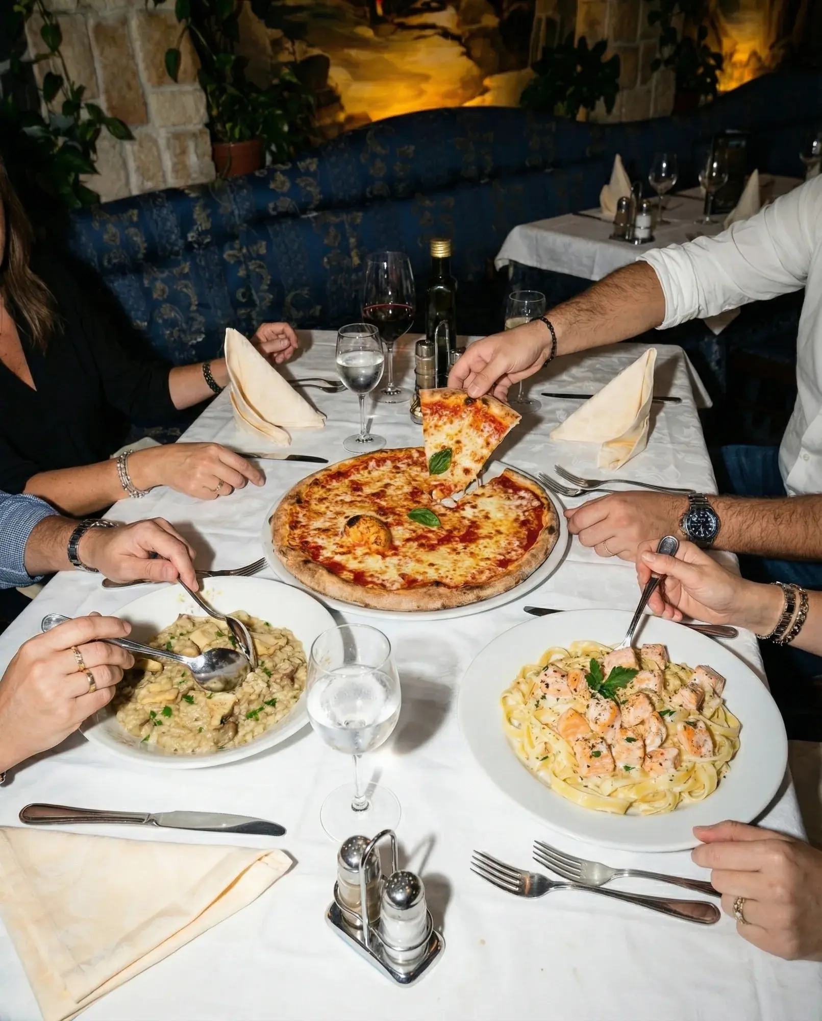 Gäste teilen Pizza, Pasta und Wein an einem Tisch bei La Commedia.